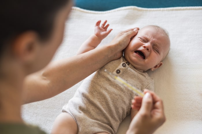 Parent soothing a crying infant lying on a blanket