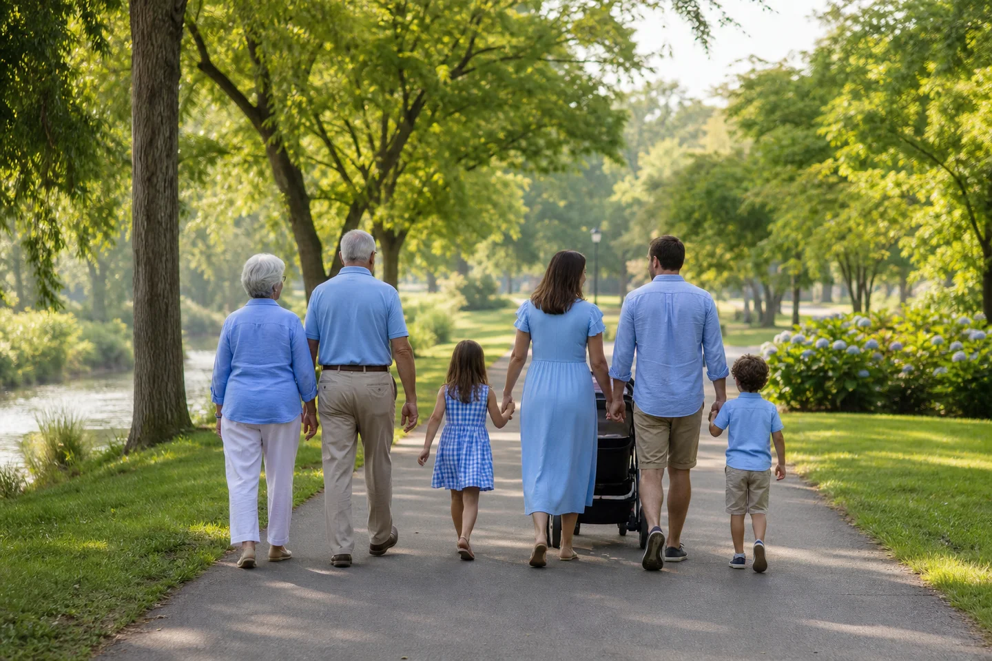 Three generations of a family walking together along a tree-shaded park path