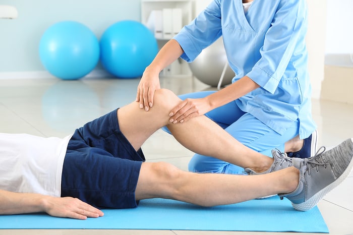 Provider examining a patient’s knee during a therapy session