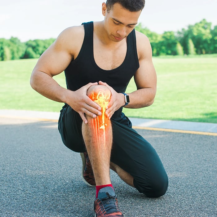 Runner kneeling on a path and clutching his painful knee