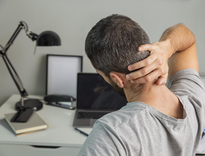 Man rubbing the back of his neck after long hours at a computer