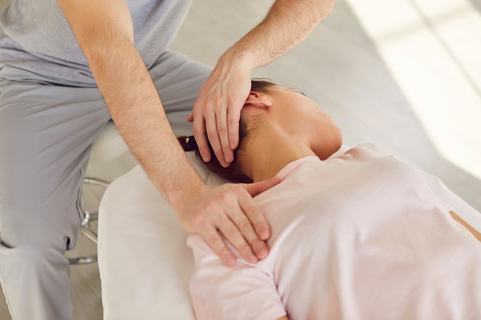 Provider giving hands-on care to a patient’s neck on a treatment table