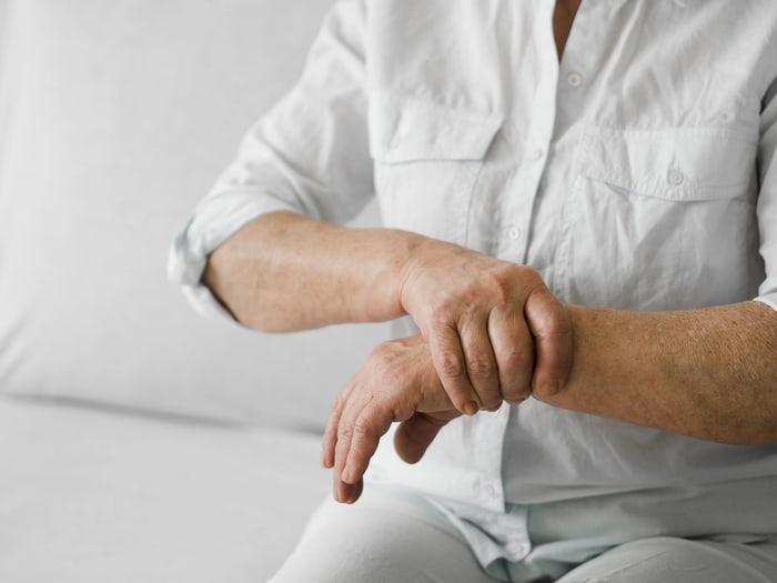Older adult gripping a wrist affected by tingling and weakness