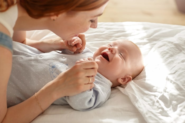 Mother smiling and playing with her calm, happy baby