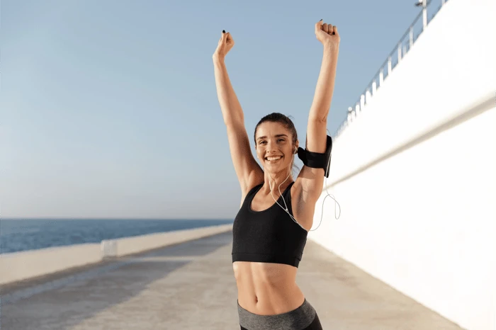 Recovered patient raising her arms in celebration outdoors