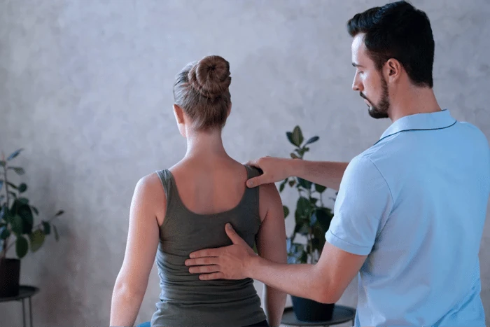 Chiropractor assessing the upper back and shoulder alignment of a standing patient