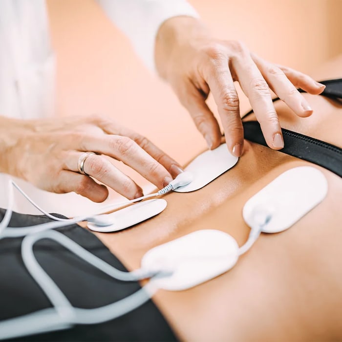 Provider placing e-stim electrode pads on a patient’s lower back