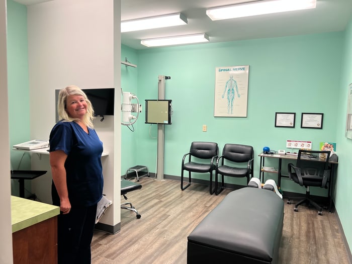 Smiling ProWellness team member in a treatment room with an adjustment table