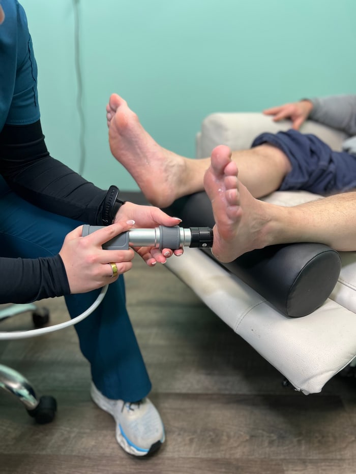 Provider applying the shockwave therapy handpiece to a patient’s foot